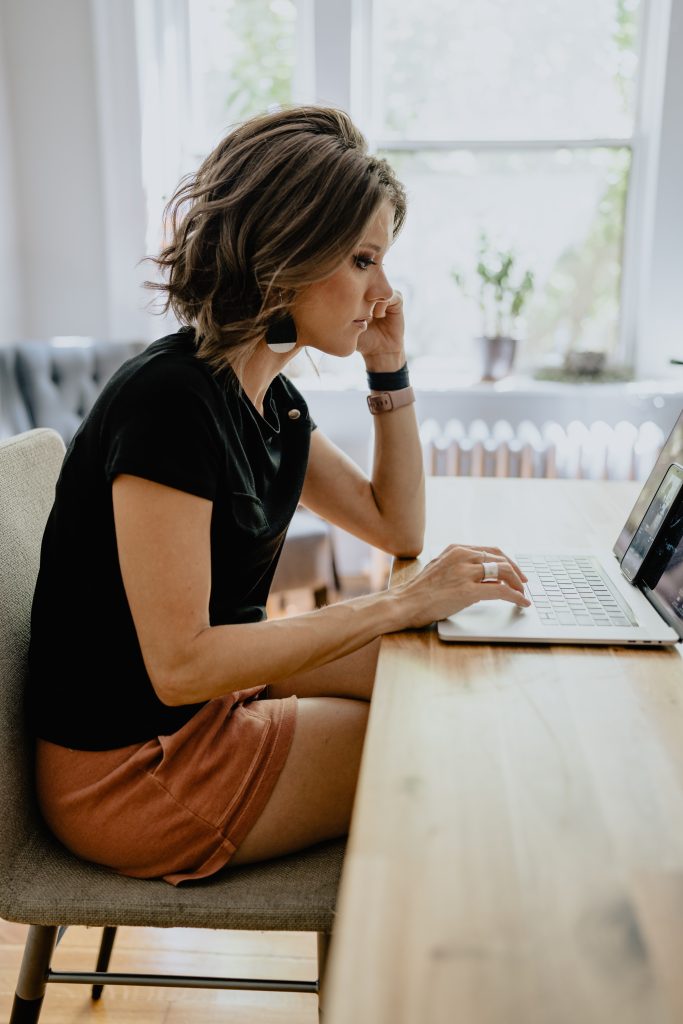 Certified German Translator Blog Post Image: White woman sitting at a table, working on a laptop.